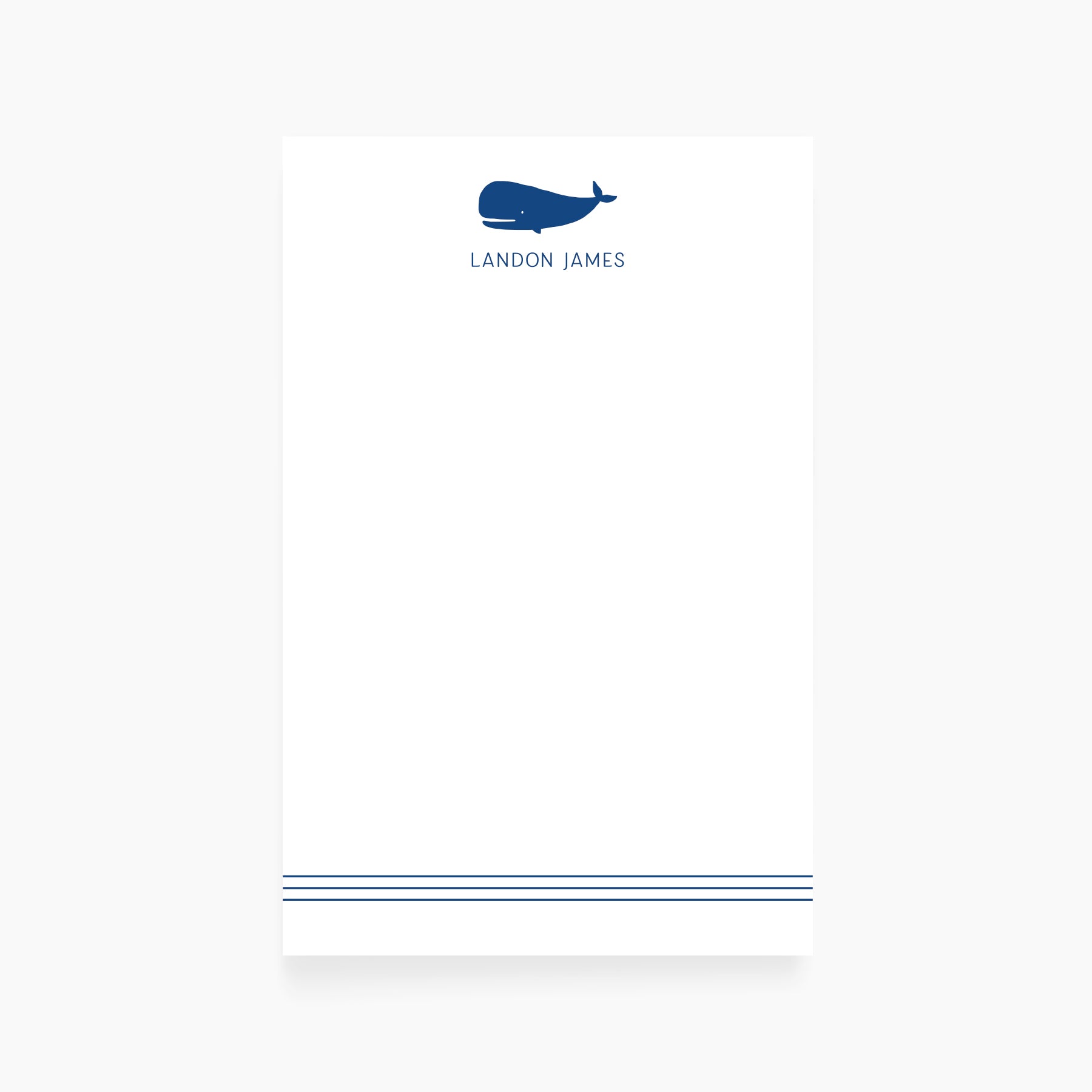 Personalized kids notepad featuring a navy whale illustration and custom name with double-line border.