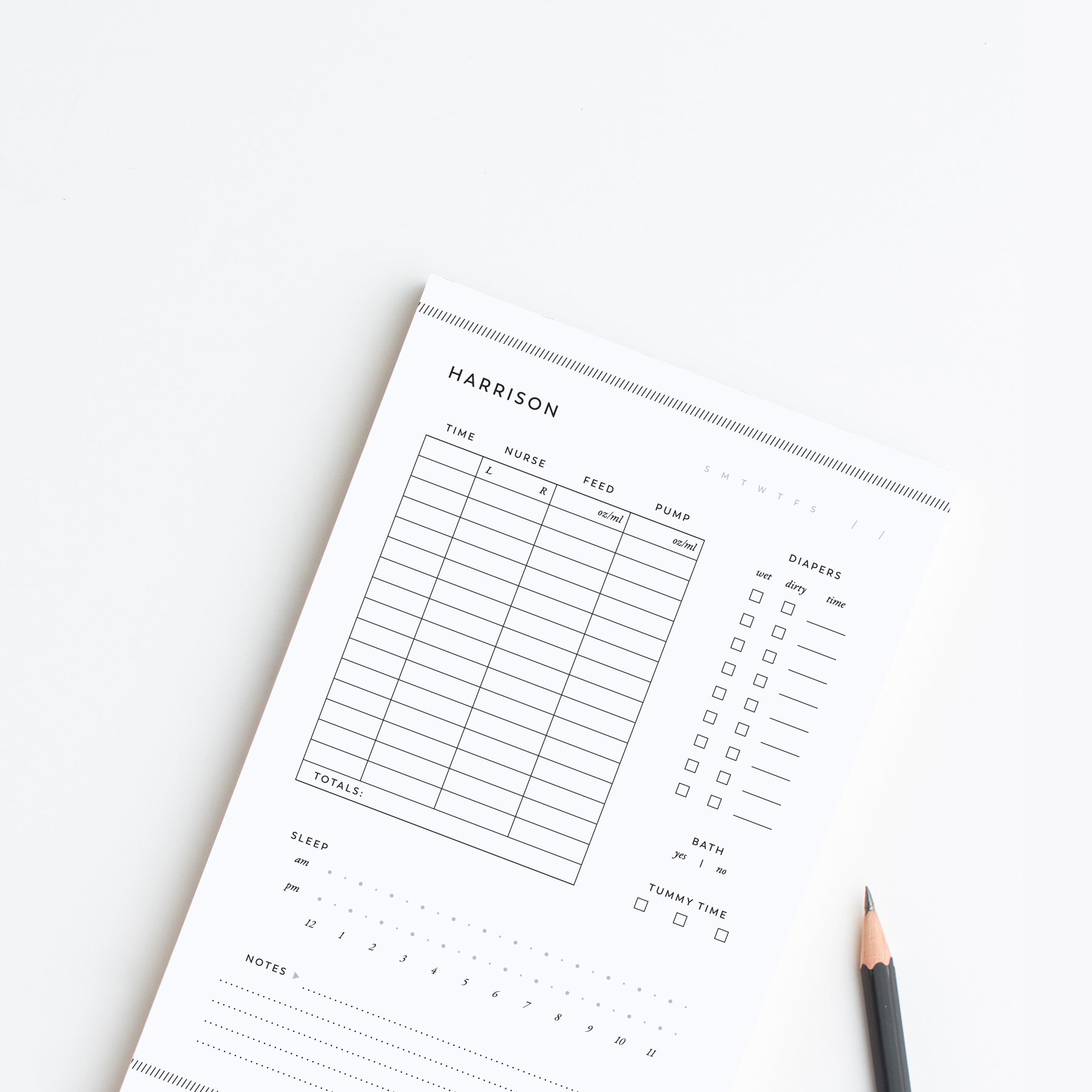 Personalized baby care log notepad with feeding and diaper tracking sections styled on white background with pencil.