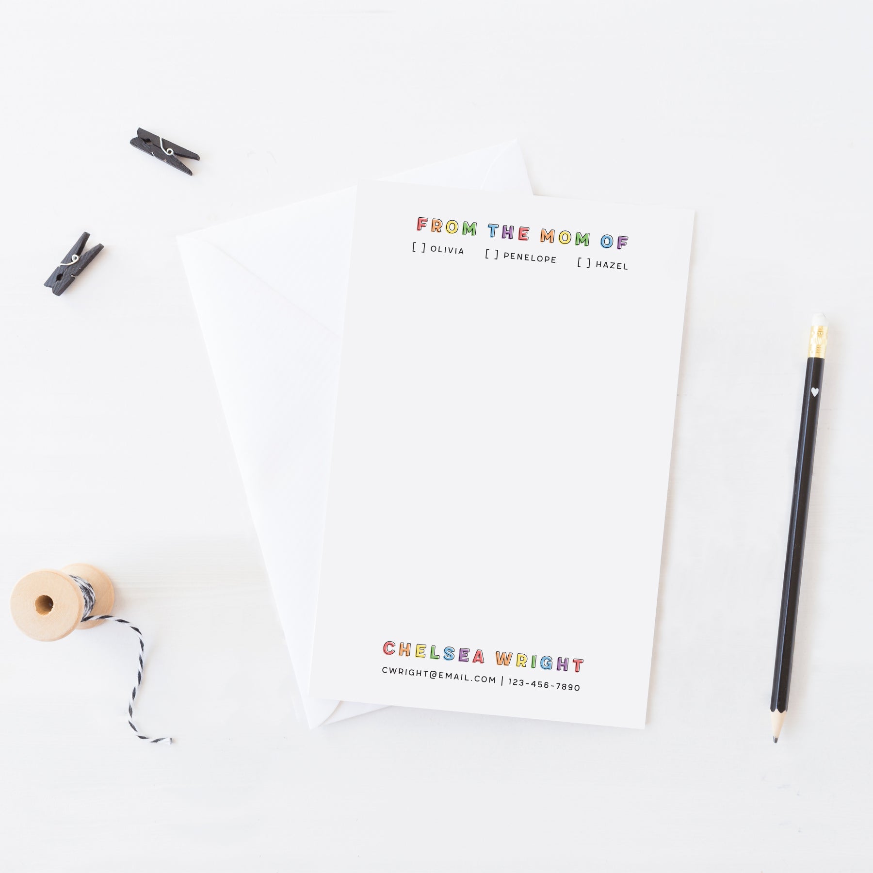 Personalized “Mom Of” notepad with rainbow block lettering, kid checkboxes, and parent contact info styled with pencil and twine.